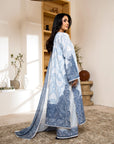 Woman wearing a blue and white traditional outfit in a room with decor elements.
