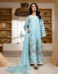 Woman in a light blue embroidered traditional outfit standing in a room with wooden shelves.