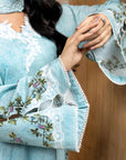 Close-up of a person wearing a light blue embroidered outfit with floral patterns.