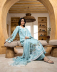 Woman in a light blue embroidered dress sitting in a modern interior setting.