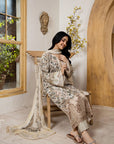Woman in a brown floral dress sitting on a chair in a room with wooden arch and window.