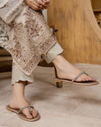 Person wearing a patterned outfit and sandals on a wooden floor.