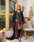 Woman in a dark floral outfit standing in a room with wooden furniture and plants.