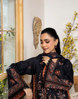 Woman wearing a black and red patterned dress standing indoors with decorative elements.