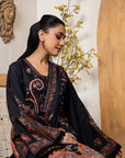 Woman wearing a black and patterned traditional outfit with a decorative background
