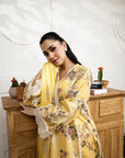 Woman in a yellow floral dress standing in a room with wooden furniture and decorative items.