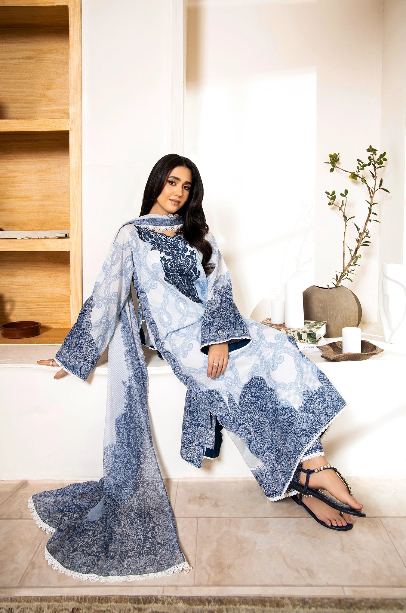 Woman wearing a blue and white patterned dress sitting on a couch in a modern living room.