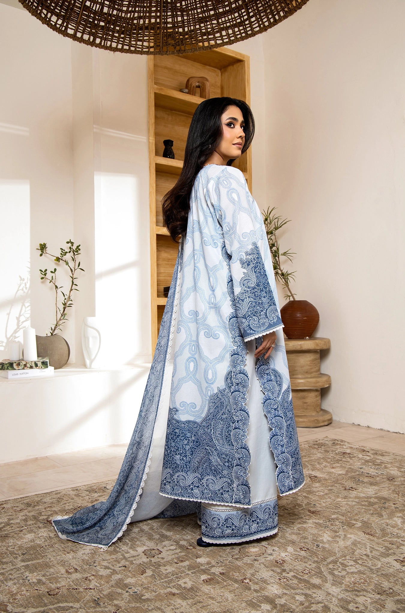 Woman wearing a blue and white traditional outfit in a room with decor elements.