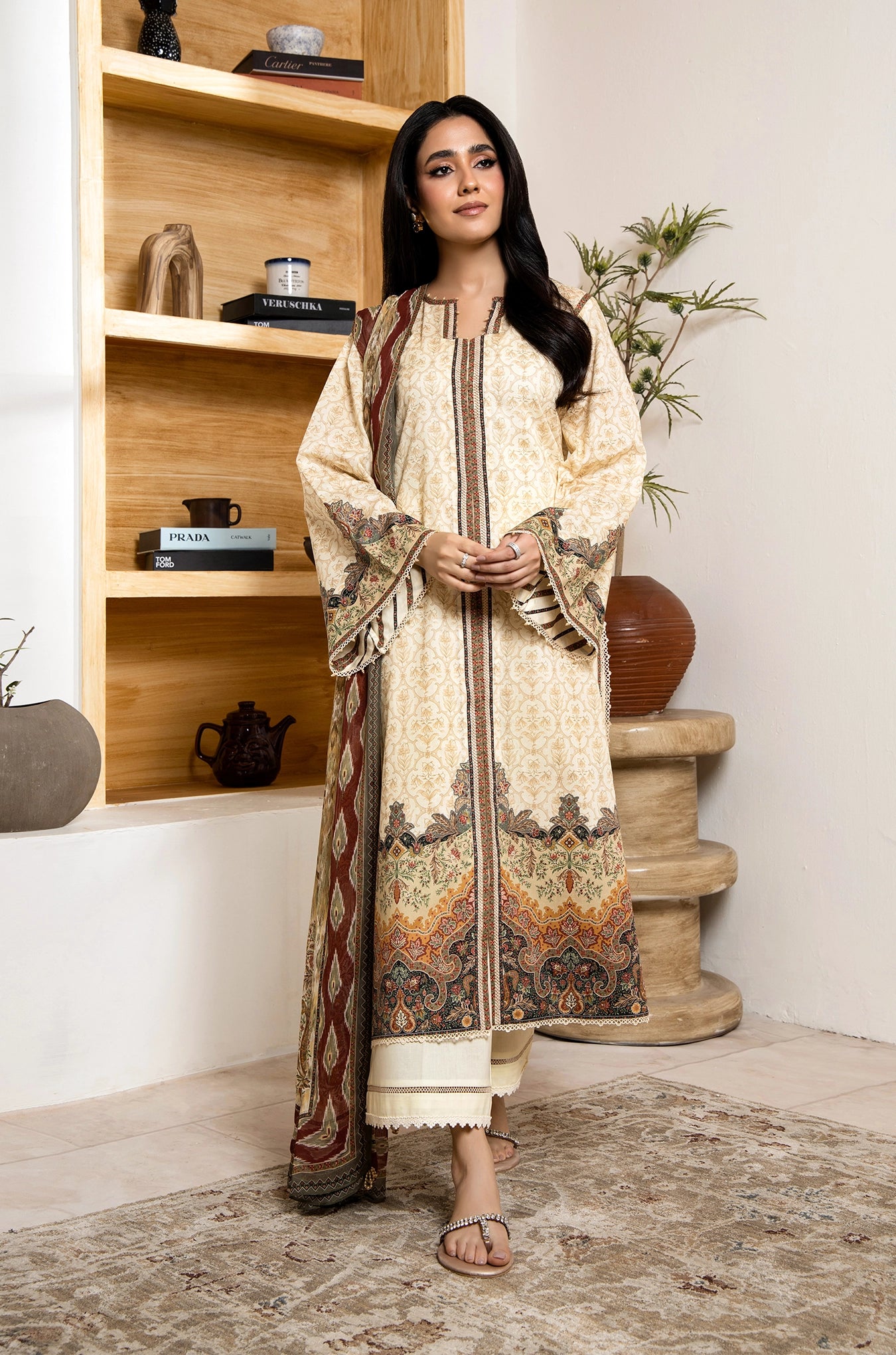 Woman in a traditional outfit standing in a room with wooden shelves and decor.