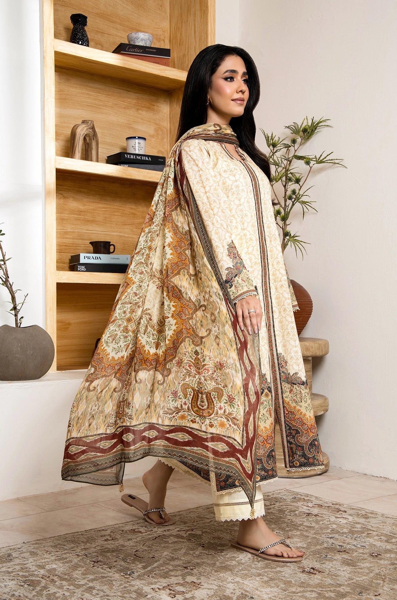 Woman in a traditional outfit standing in a room with wooden shelves and decor.