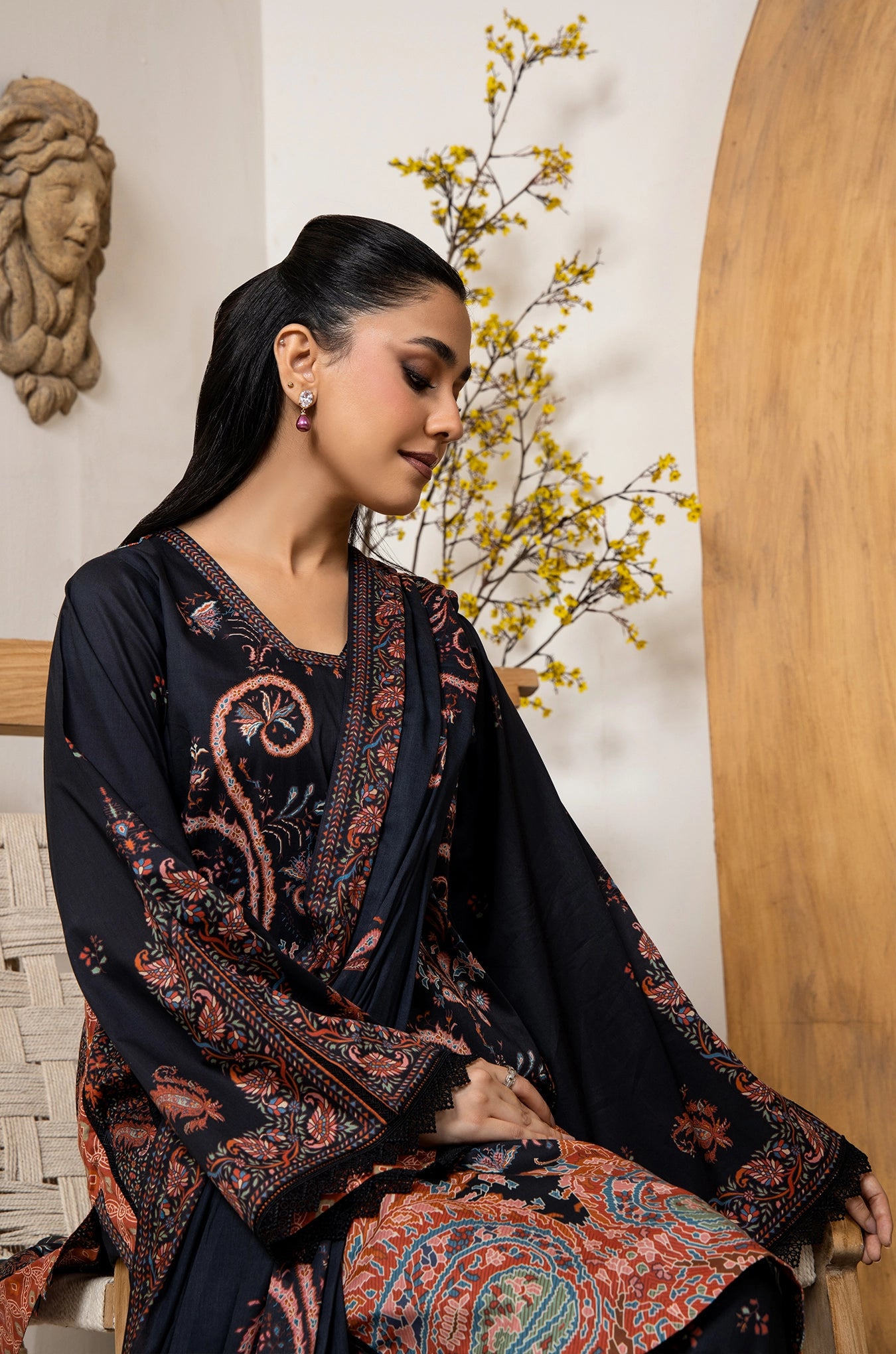 Woman wearing a black and patterned traditional outfit with a decorative background