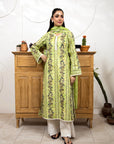 Woman in a green floral dress standing in front of a wooden cabinet with decorative plants.