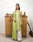Woman in a green floral dress standing in front of a wooden cabinet with decorative items.